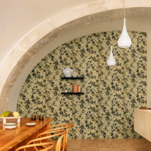 Woonkamer met gebogen stenen plafond, houten eettafel en Buningh Elitis Milos behang met bloemmotief op de achterwand.