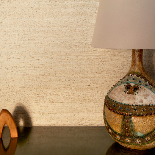 Decoratieve lamp en houten object voor een wand met Buningh Elitis Ortigia Travertin crème behang.