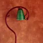 Groene lamp aan een gebogen rode standaard tegen rood Buningh-Elitis Ortigia Agrigente vp 960 behang.