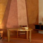 Sfeervolle interieurhoek met een houten bureau en abstract Buningh Elitis Osorno VP 963 03 behang uit de Ortigia collectie.