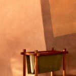 Detail van het Buningh Elitis Osorno VP 963 03 behang uit de Ortigia collectie met een houten tijdschriftenhouder op de voorgrond.