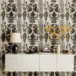 Wand met Buningh-Elitis Paros behang uit de Lin Brodés collectie, met zwart botanisch patroon en een modern wit dressoir met decoratieve accessoires.