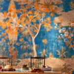 Sfeervolle eetkamer met het kleurrijke 'Retour des Indes' behang uit de Ortigia-collectie van Buningh-Elitis als opvallende achtergrond.