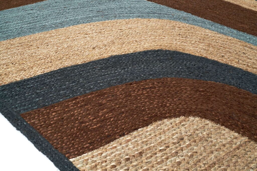 Detail van het Elitis vloerkleed Penny Lane in blauw en aardetinten met golvend patroon.