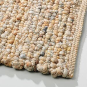 Detailopname van het Perletta Boulder vloerkleed van Buningh Wonen met grove wollen lussen in beige- en aardetinten.
