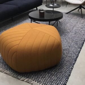 Gezellige zithoek met een blauw Perletta Doppio vloerkleed, ronde zwarte salontafels en een grote oranje poef.