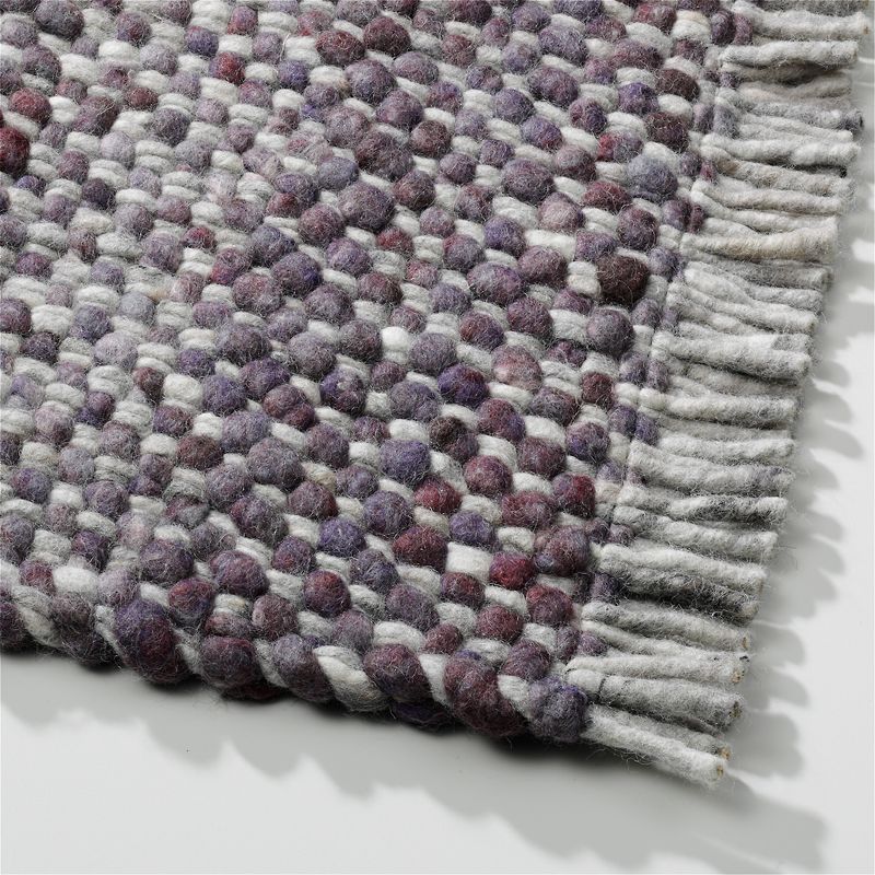 Detail van het Perletta Garno 499-01 vloerkleed met dik geweven structuur in grijs-, paars- en wittinten en franjes aan de rand.