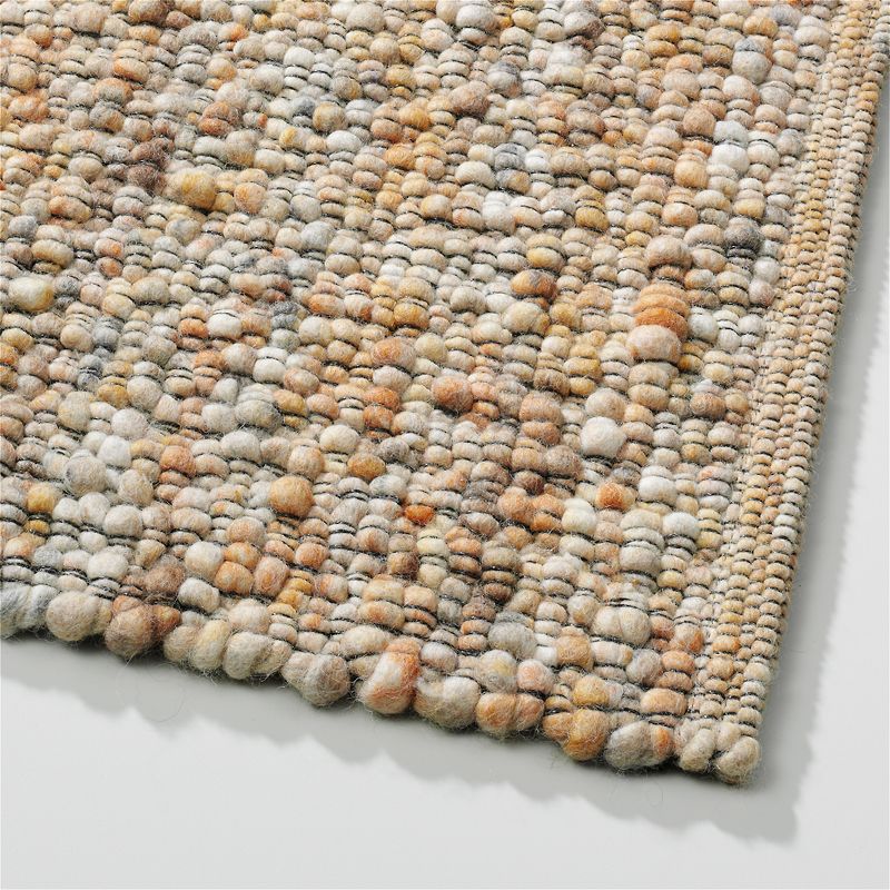 Detail van het Perletta vloerkleed Gravel 423 in de kleur honey met grove, handgeweven structuur en warme tinten.