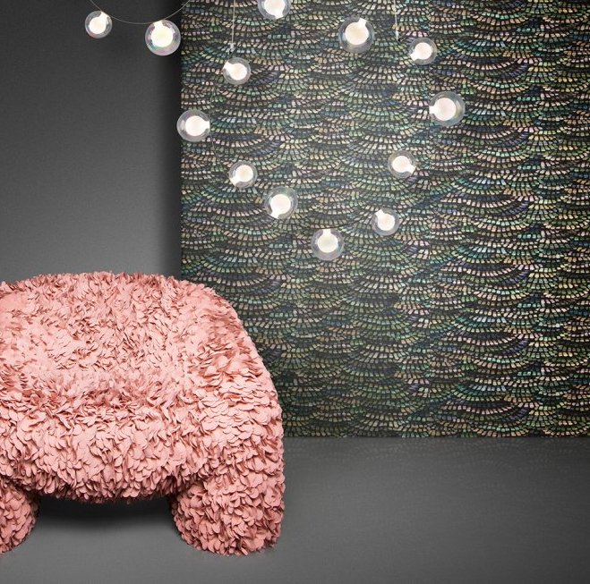 Roze designstoel met bloemblaadjesstructuur voor een wand met Arte Moooi Dandelion Cranes behang en hangende sfeerverlichting.