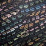 Detail van het Arte Moooi Dandelion Cranes behang met kleurrijk patroon op een zwarte, geplooide ondergrond.