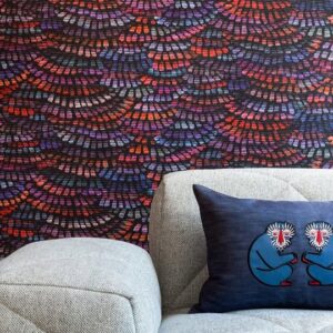 Grijze bank met blauw kussen met apenmotief, voor een kleurrijk Arte Moooi Dandelion Cranes-behang.