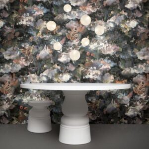 Witte design tafel en kruk voor een donkere, bloemrijke muur met Moooi Memento behang van Arte.