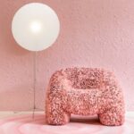 Roze designfauteuil met bloemachtig textuurontwerp van Moooi, voor een roze muur met Arte Mimic Moth behang en een grote ronde vloerlamp.