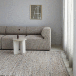 Neutraal interieur met een Perletta Neon vloerkleed, beige bank en wit bijzettafeltje in een lichte woonkamer.