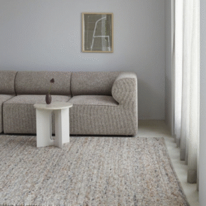 Neutraal interieur met een Perletta Neon vloerkleed, beige bank en wit bijzettafeltje in een lichte woonkamer.