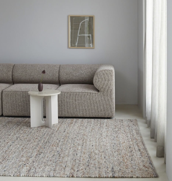 Neutraal interieur met een Perletta Neon vloerkleed, beige bank en wit bijzettafeltje in een lichte woonkamer.