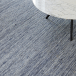 Close-up van een blauw Perletta Spot vloerkleed met een wit marmeren salontafel erop.