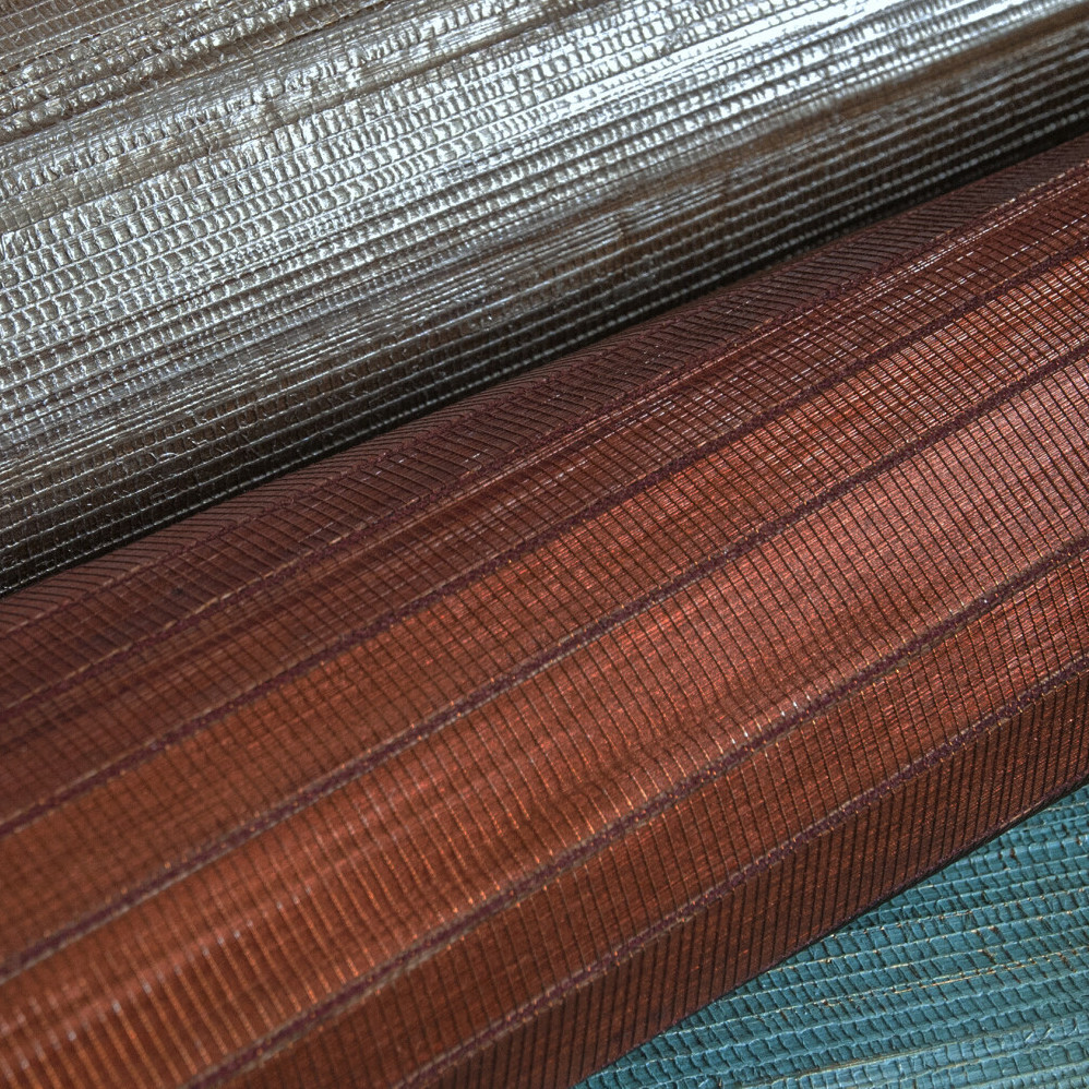 Close-up van drie opgerolde vellen Carabao M1-materiaal in metallic zilver, koperbruin en blauwgroen met een fijne textuur.