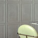 Grijze wand met geometrisch paneelpatroon (Cassetta2-FWXC-2) naast een lichtgele stoel en een tafel met marmeren blad.