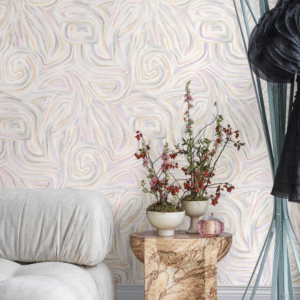 Zithoek met abstracte Cole and Son Kawakubo-behang, marmeren bijzettafel, bloeiende takken in vazen en een zachte beige fauteuil.