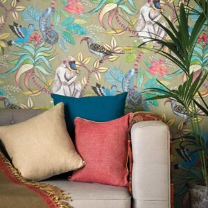 Bank met kleurrijke kussens tegen een exotisch behang met dieren en planten uit het Cole and Son Ardmore Savuti ontwerp.