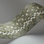 Decoratieve strook van Cole and Son Ardmore border behang met groen, wit en goud geometrisch en floraal patroon.