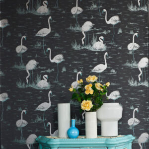 Donkerbehang met witte flamingo’s uit de Cole and Son Flamingos-collectie, gecombineerd met een turquoise kast en vaasjes met gele rozen.
