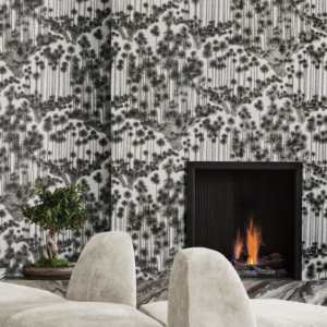 Modern interieur met behang 'Japanese Woods' van Cole and Son, een brandend haardvuur en een bonsaiboom op de voorgrond.