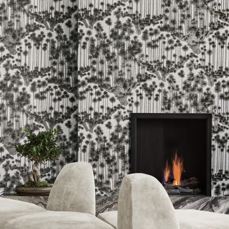 Modern interieur met behang 'Japanese Woods' van Cole and Son, een brandend haardvuur en een bonsaiboom op de voorgrond.