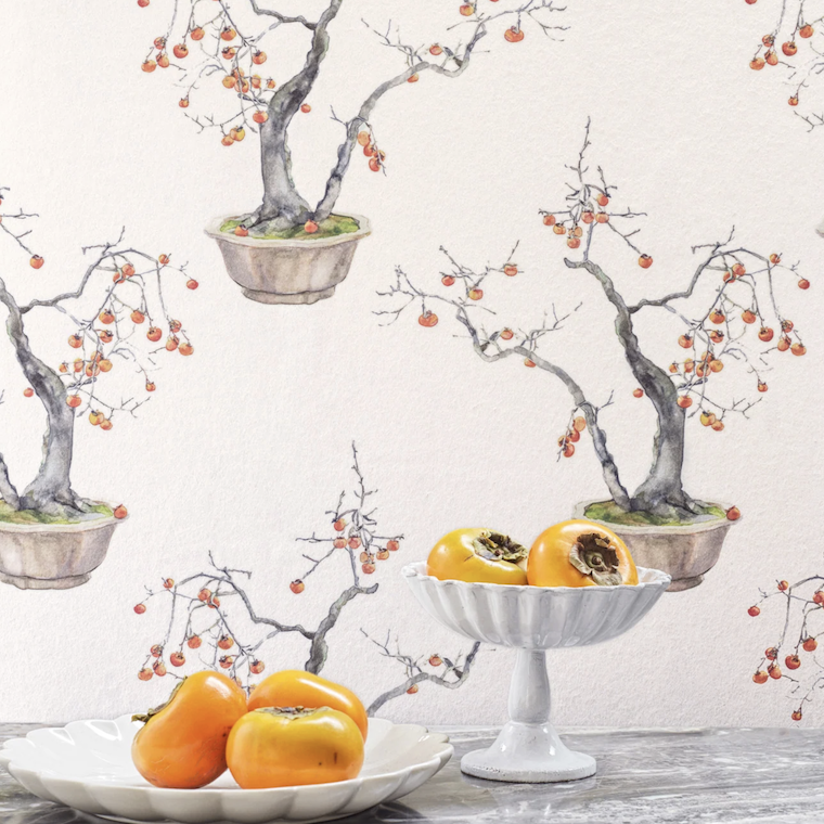 Sfeervolle interieursetting met Cole and Son Kaki Persimmon behang en geserveerde kakivruchten op een marmeren tafel.