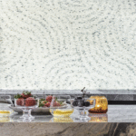 Gedekte marmeren tafel met glazen kommen fruit en kaars, voor een Cole and Son Meditation Stone behang in rustgevend patroon.