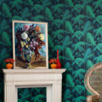 Woonkamer met Cole and Son Palm Jungle-behang, een witte schouw en een schilderij met bloemen.