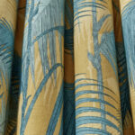 Stof met een tropisch palmbladpatroon in blauwgroene tinten op een gele achtergrond uit de Cole and Son Palm Jungle collectie.