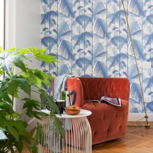 Oranje fluwelen fauteuil in een stijlvolle woonkamer met Cole and Son Palm Jungle behang en tropische accenten.