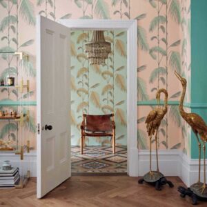 Interieur met Cole and Son Palm Leaves Icons-behang, gouden vogelbeelden en een leren stoel in een kleurrijke kamer.