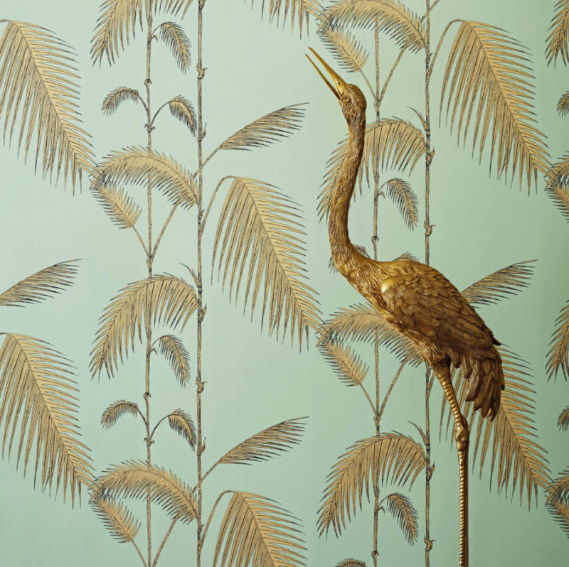 Goudkleurige reigerlamp voor een mintgroene Cole and Son Palm Leaves Icons-behang met palmblaadjesmotief.