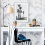 Moderne werkplek met een witte desk, zwart-witte stoel en Cole and Son Palm Leaves behang op de achtergrond.