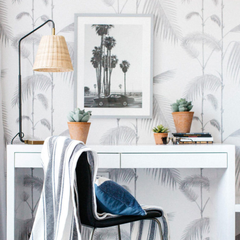 Moderne werkplek met een witte desk, zwart-witte stoel en Cole and Son Palm Leaves behang op de achtergrond.