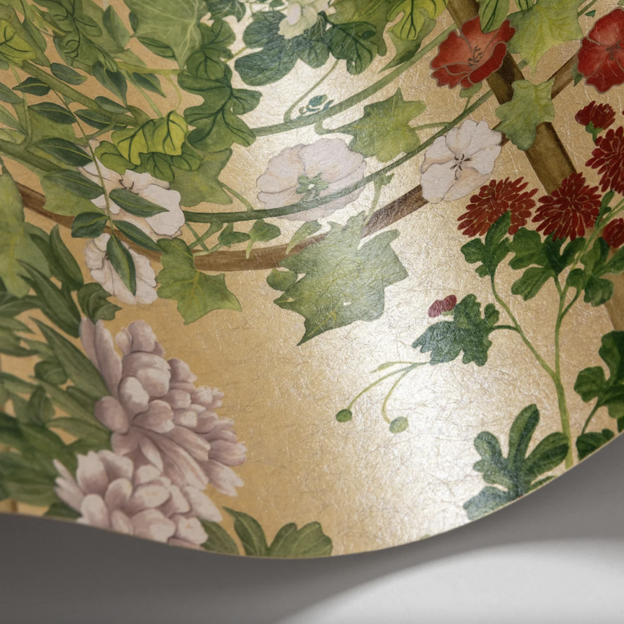 Detail van het Cole and Son Scenic Flora Gilded behang met kleurrijke bloemen en groene bladeren op een goudkleurige achtergrond.