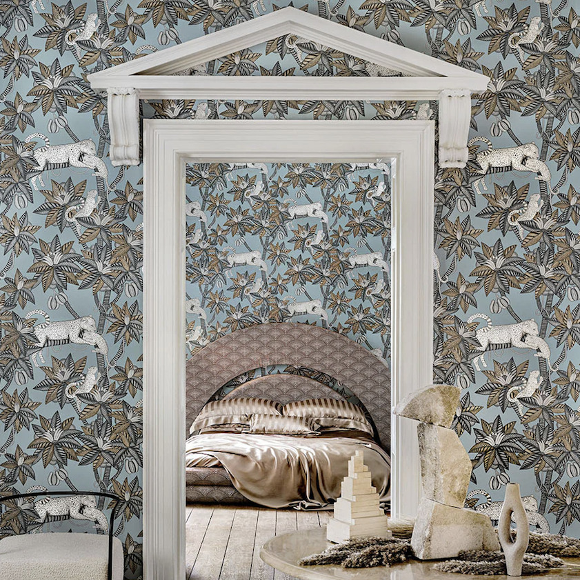 Sfeervolle slaapkamer met Cole and Son Ardmore Jabula 119/3012 Satara behang met luipaard- en bladerpatroon op een lichtblauwe achtergrond.