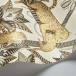 Detail van het Cole and Son Ardmore Jabula Satara behang met illustraties van luipaarden en gestileerde tropische bladeren in bruin- en goudtinten.