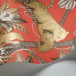 Detail van het Cole and Son Ardmore Jabula behang met luipaarden en gestileerde bladeren op een felrode achtergrond.