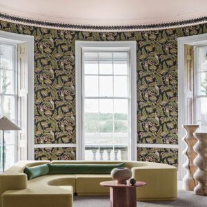 Ronde kamer met grote ramen, modern meubilair en Cole and Son Ardmore Jabula 119/7031 Bush Baby behang met een exotisch patroon.
