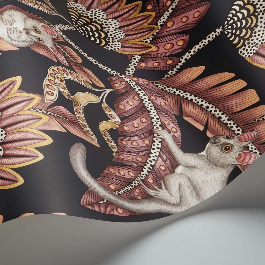 Gedetailleerd behangontwerp uit de Cole and Son Ardmore Jabula serie met Bush Baby figuren tussen gestileerde bladeren en bloemen in roze, goud en zwarttinten.