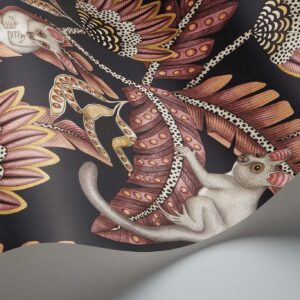 Gedetailleerd behangontwerp uit de Cole and Son Ardmore Jabula serie met Bush Baby figuren tussen gestileerde bladeren en bloemen in roze, goud en zwarttinten.