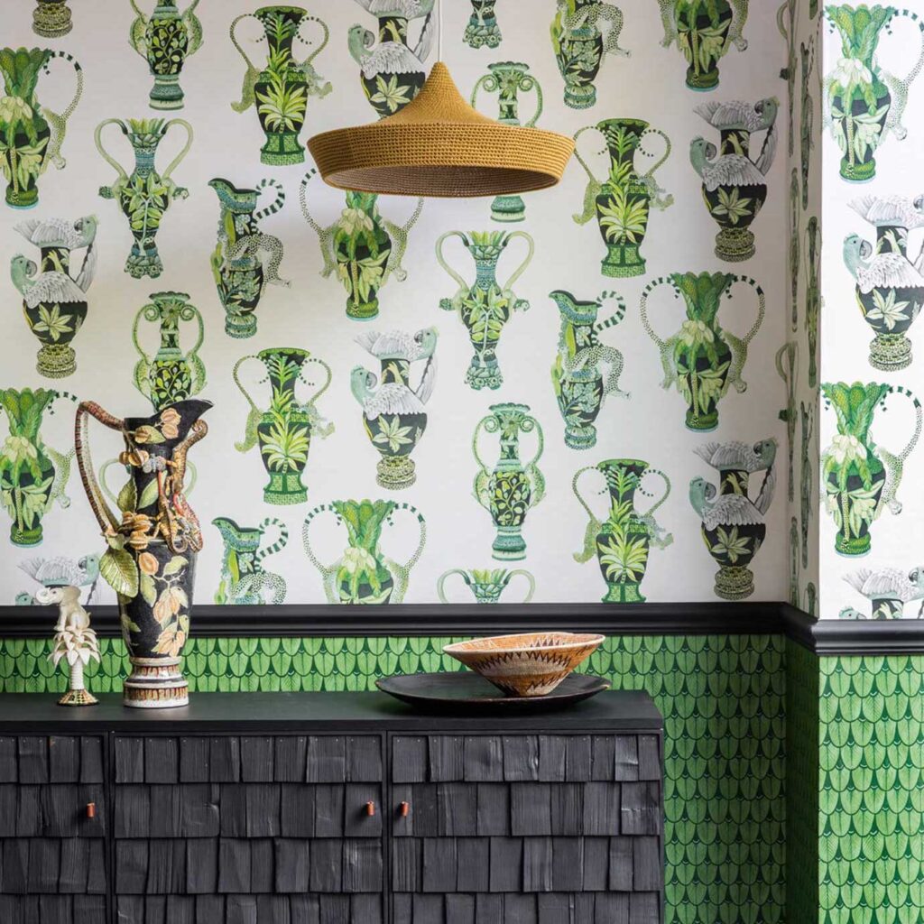 Woonkamer met Cole and Son Ardmore Khulu Vases behang in groentinten, met decoratieve vazen en dierenmotieven.