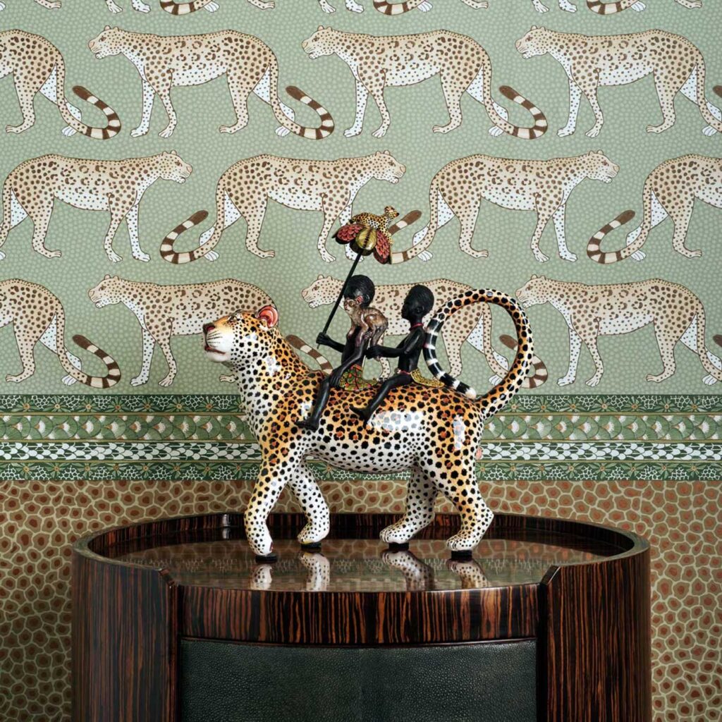 Decoratief beeld van twee figuren op een luipaard voor Cole and Son Ardmore Leopard Walk behang met luipaardpatroon.
