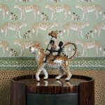 Decoratief beeld van twee figuren op een luipaard voor Cole and Son Ardmore Leopard Walk behang met luipaardpatroon.