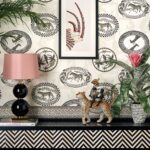 Interieur met Cole and Son-behang Ardmore Matrinah, een zwart-witte dierenprint, gecombineerd met tropische decoraties en een lamp met roze kap.