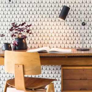 Houten bureau met open boek, moderne bureaulamp en Ardmore Narina behang van Cole and Son op de achtergrond.